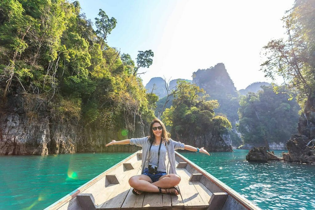 A woman sitting on a boat with her arms outstretched.