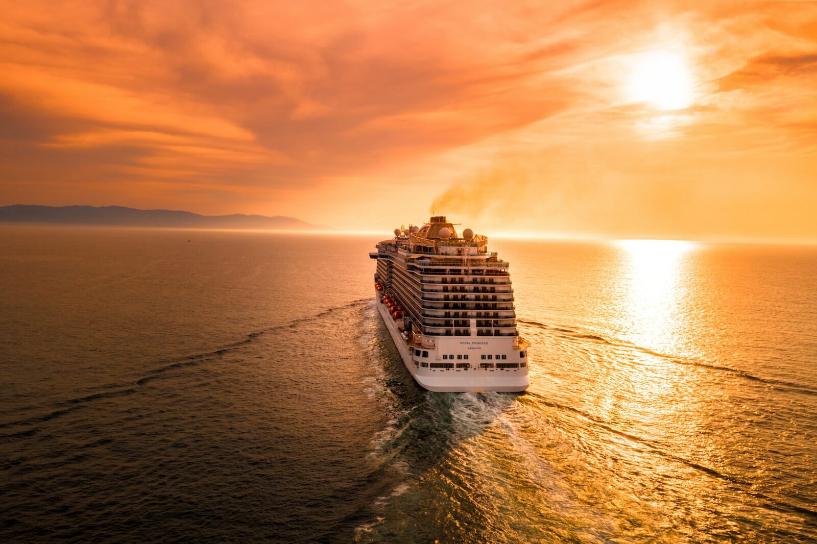 A luxurious cruise ship sailing on the calm Mediterranean Sea at sunset