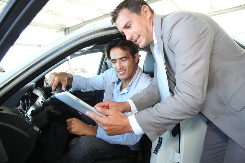 Car seller with car buyer looking at electronic tablet — Photo