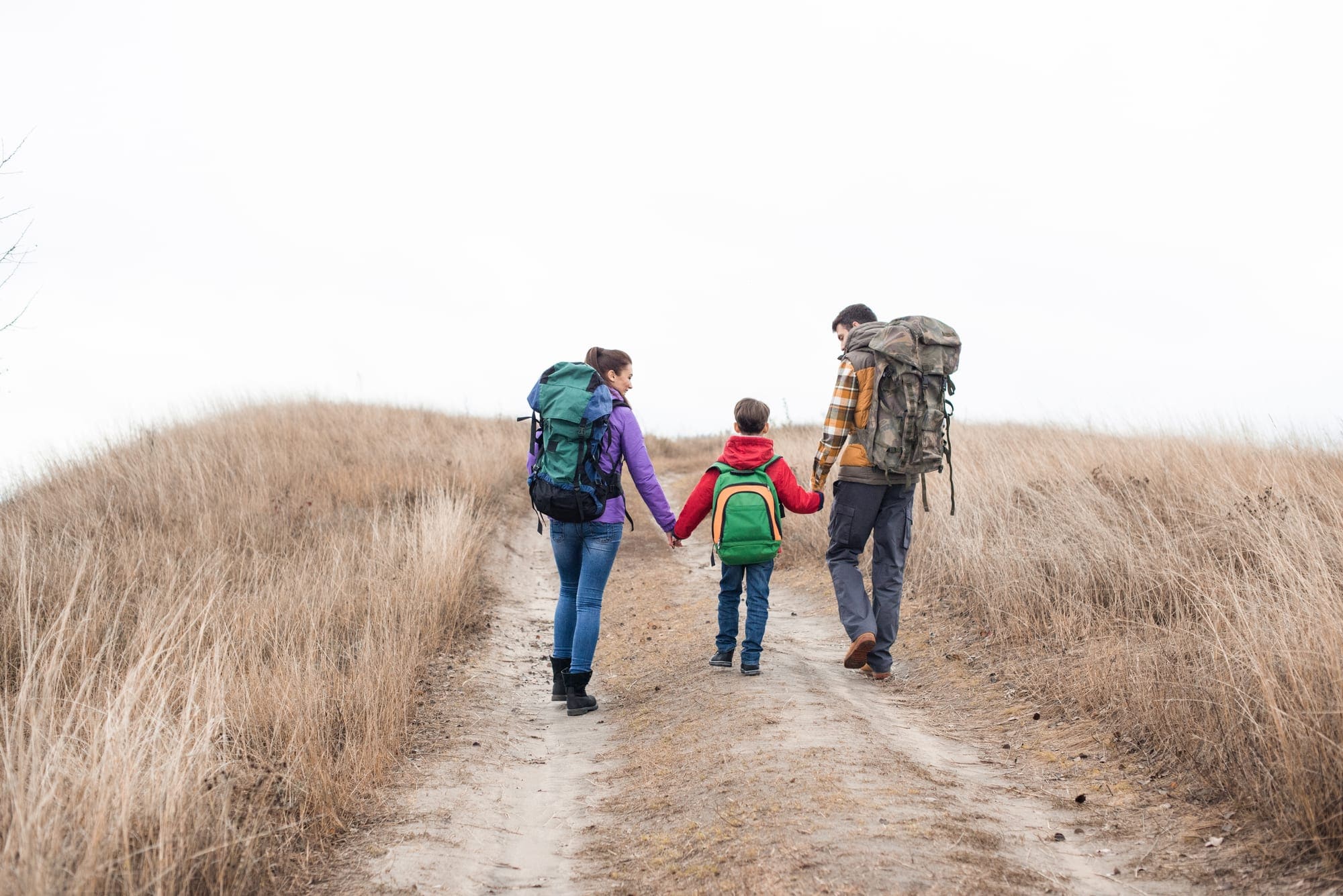 Family with backpacks walking on rural path — Photo