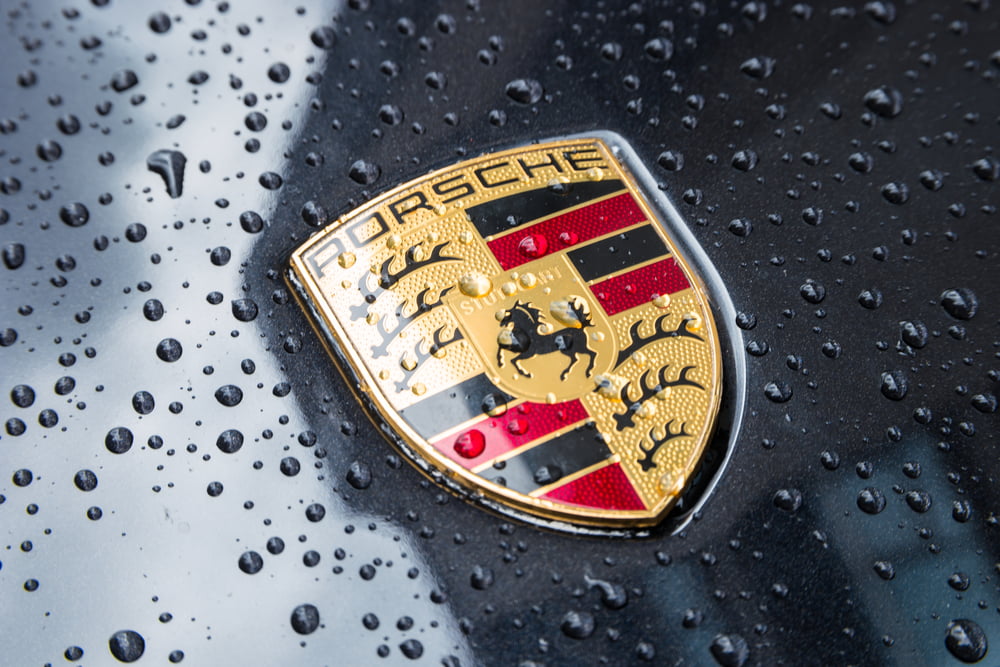 Porsche Logo Close Up on a black car with rain drops