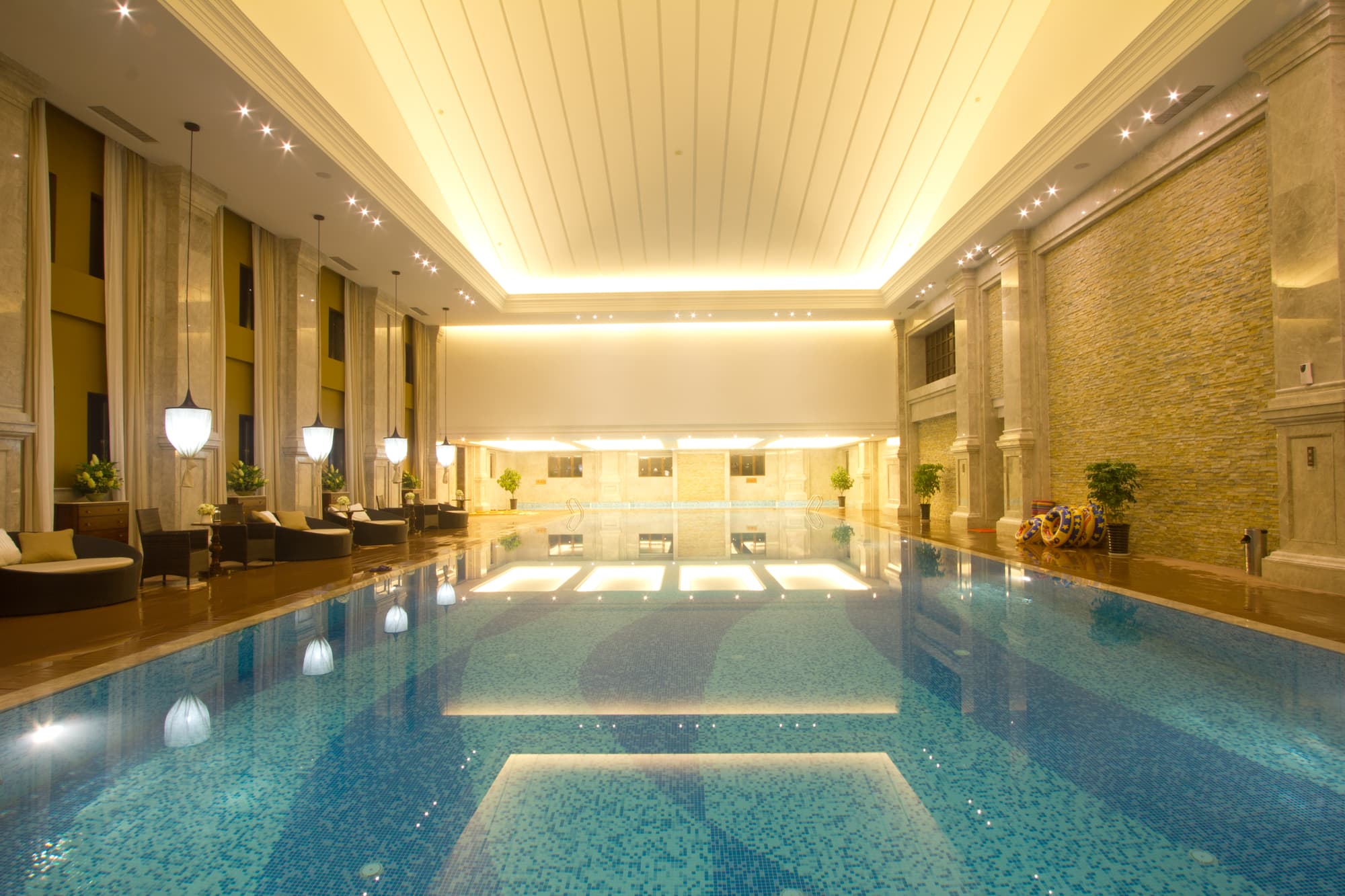A luxurious indoor swimming pool with a large ceiling and a large stone wall.