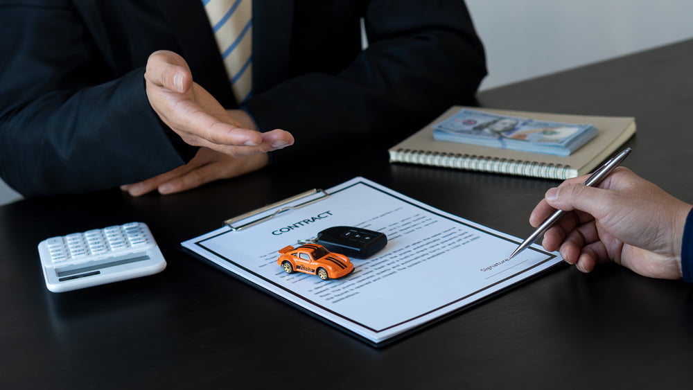 The car salesman discusses the contract with the customer. On car rental deals gestures and people close up of dealer handing oveer the keys Selling and Renting Ideas — Photo