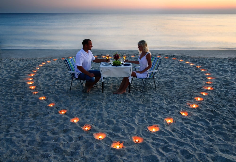 A young lovers couple share a romantic dinner with candles heart — Photo