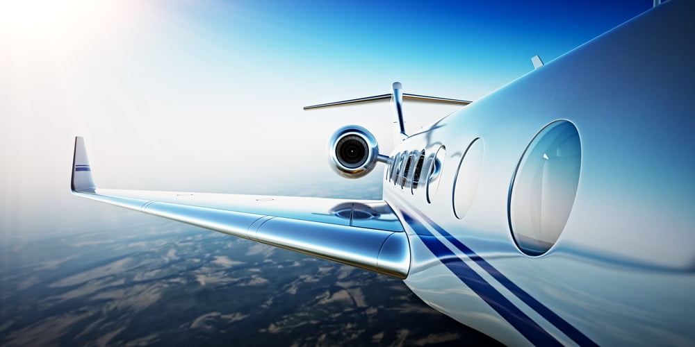 Closeup Photo of White Luxury Generic Design Private Aircraft Flying in Blue Sky at sunrise.Uninhabited Desert Mountains Background.Business Travel