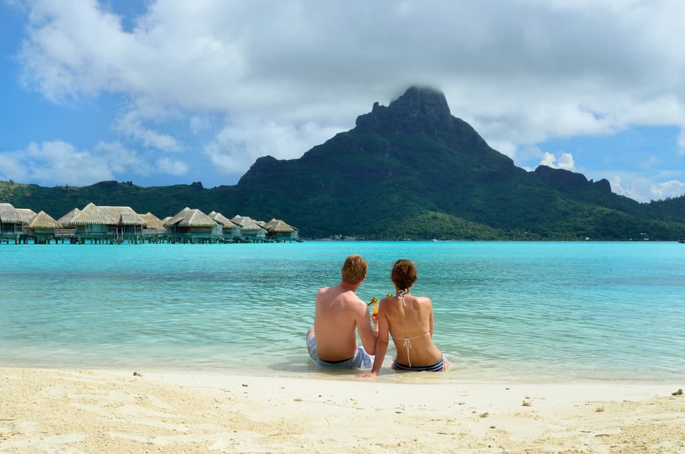 Couple of tourists on the beach in Bora Bora, one of the very famous luxury honeymoon destinations — Photo