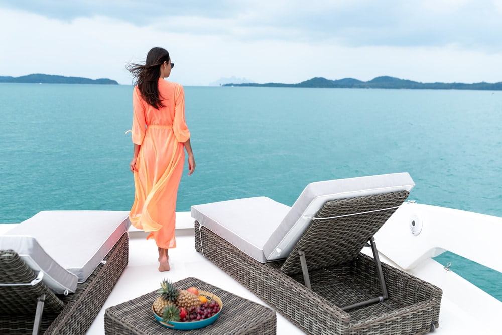 Travel to hot countries. A young woman in an orange cape stands on the edge of the yacht and admires the horizon. — Photo