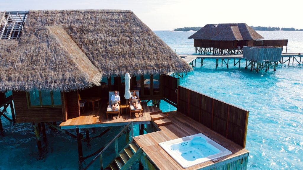 Enjoying luxury vacation packages sitting near a brown wooden house near body of water during daytime