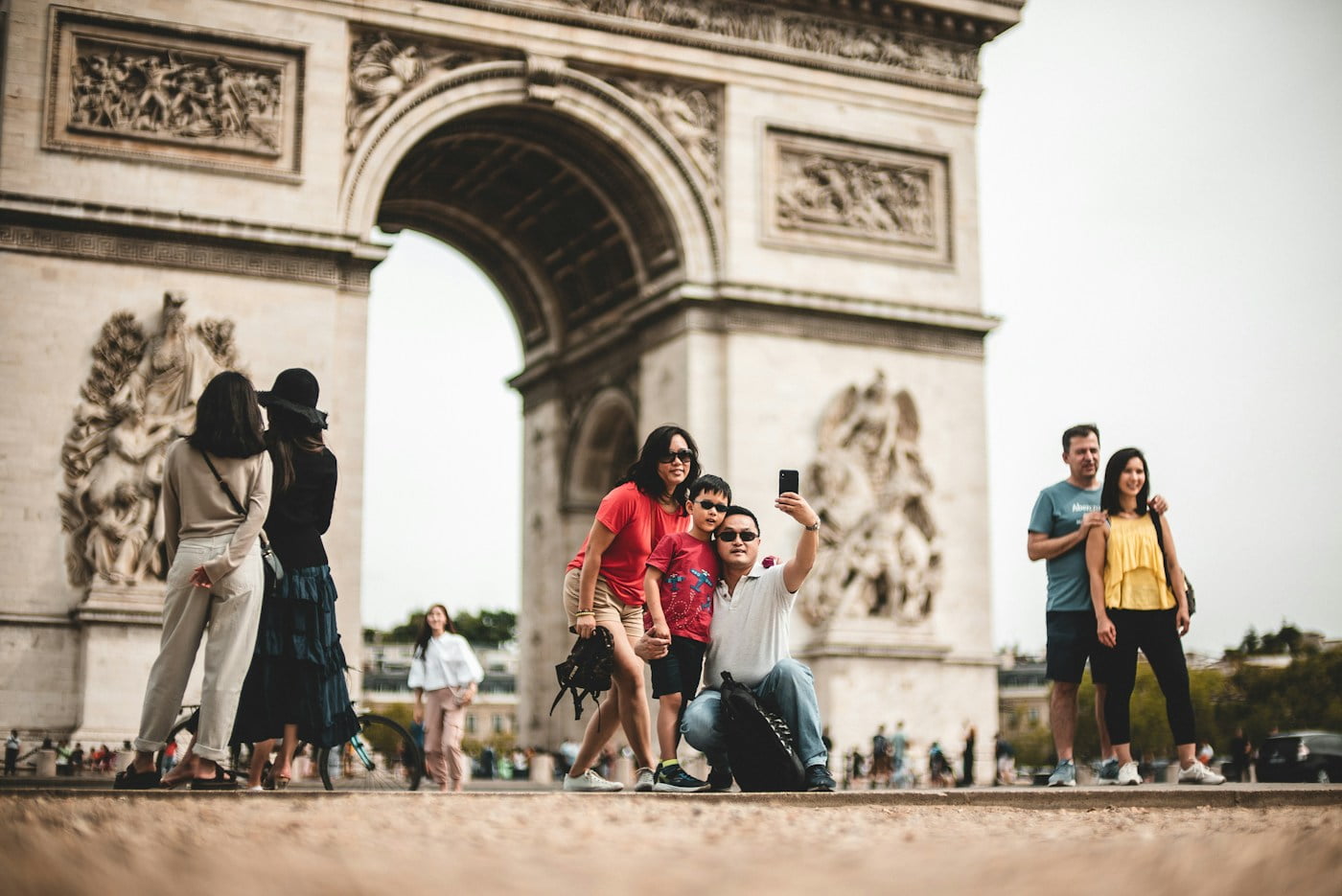 A family taking pictures in front of the arc de triomphe.