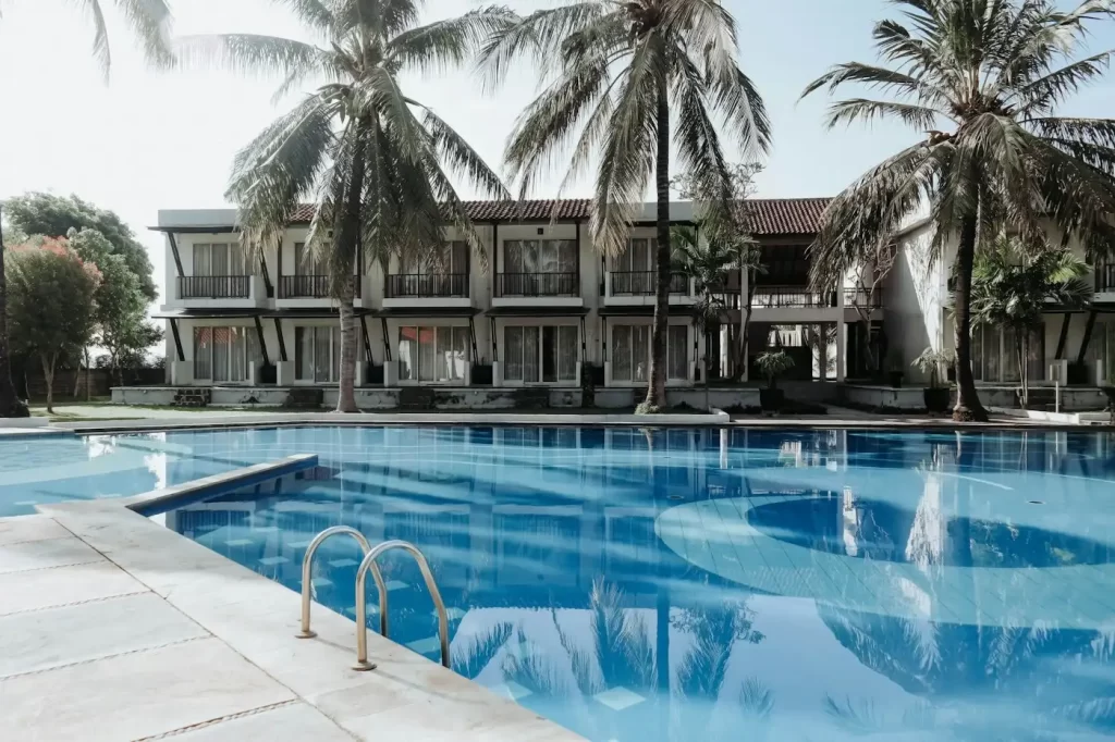 A small luxury swimming pool surrounded by palm trees, by small luxury hotels