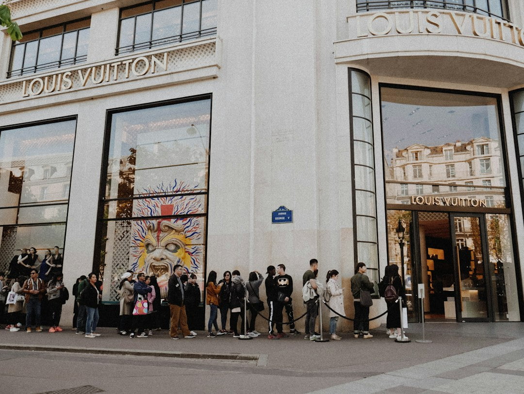 A line of people waiting outside of a louis vuitton store.