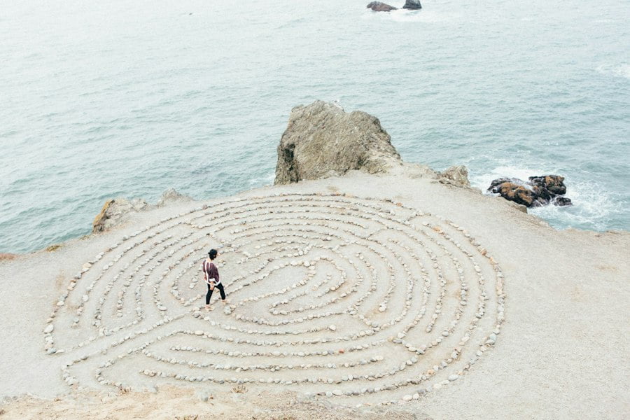 A person standing on a cliff next to a labyrinth.