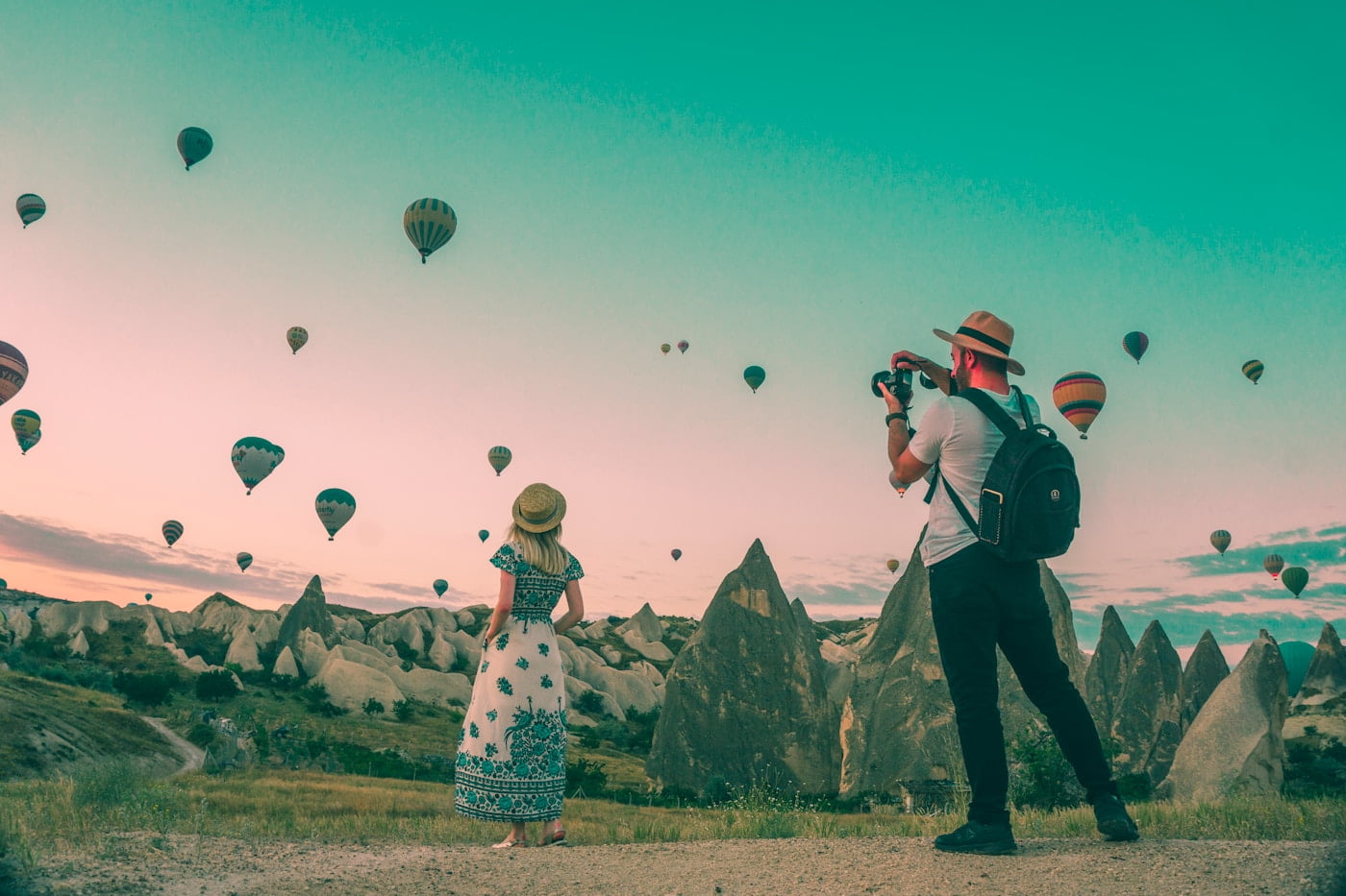A couple capturing stunning photos of hot air balloons in luxurious Cappadocia, Turkey.