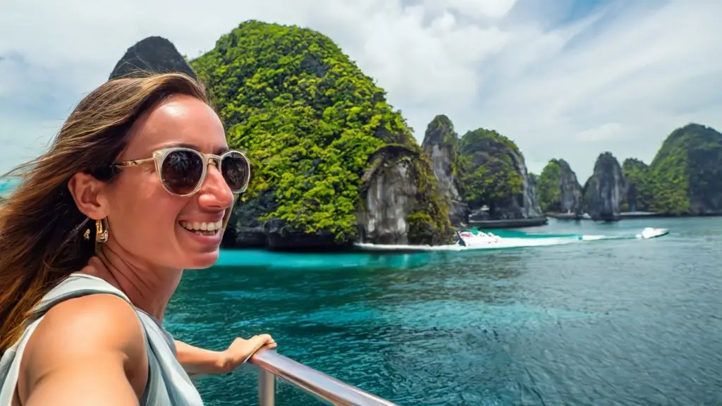 Woman smiling on a boat with scenic tropical islands in the background during her cheap luxury vacations.