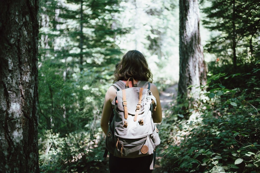 A woman walking through the woods with a backpack, seeking tips for solo travelers.